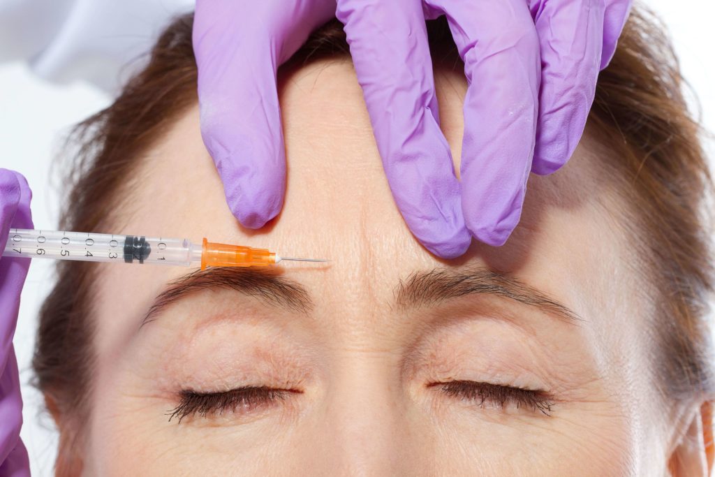 middle-aged woman getting botox between her eyebrows