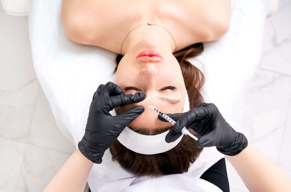 woman lying down and receiving botox injections in her forehead